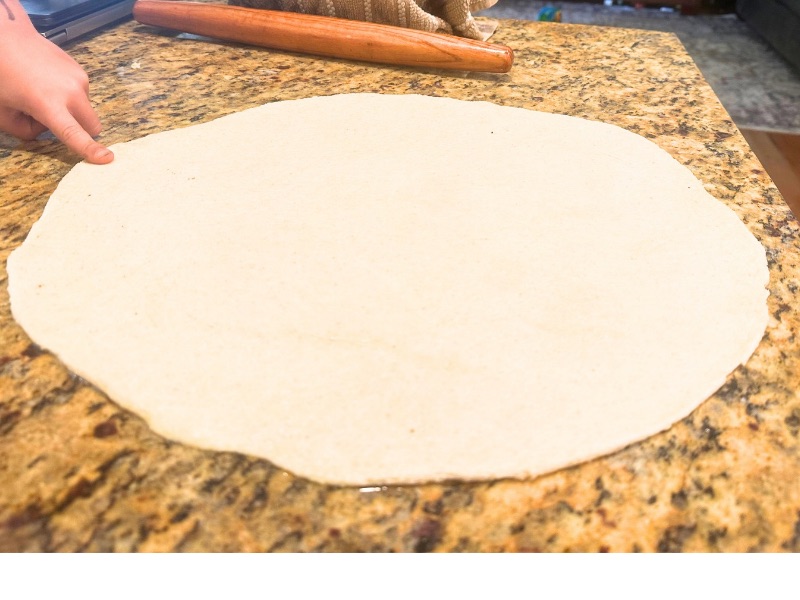 rolled out pizza dough in process image