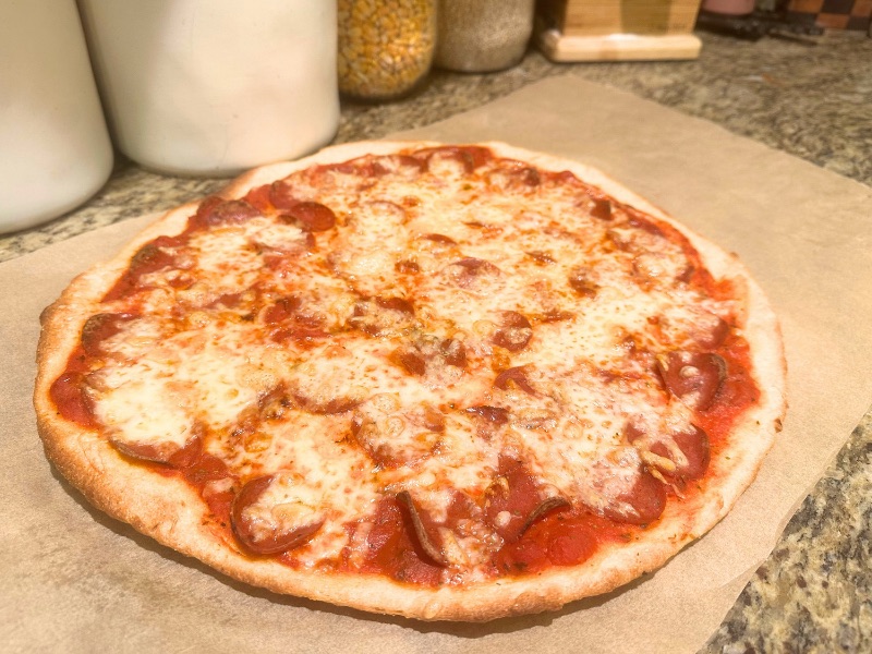 finished pizza on countertop onto of a sheet of parchment paper
