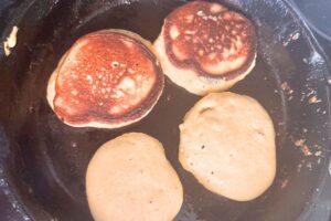 pancakes cooking in cast iron skillet
